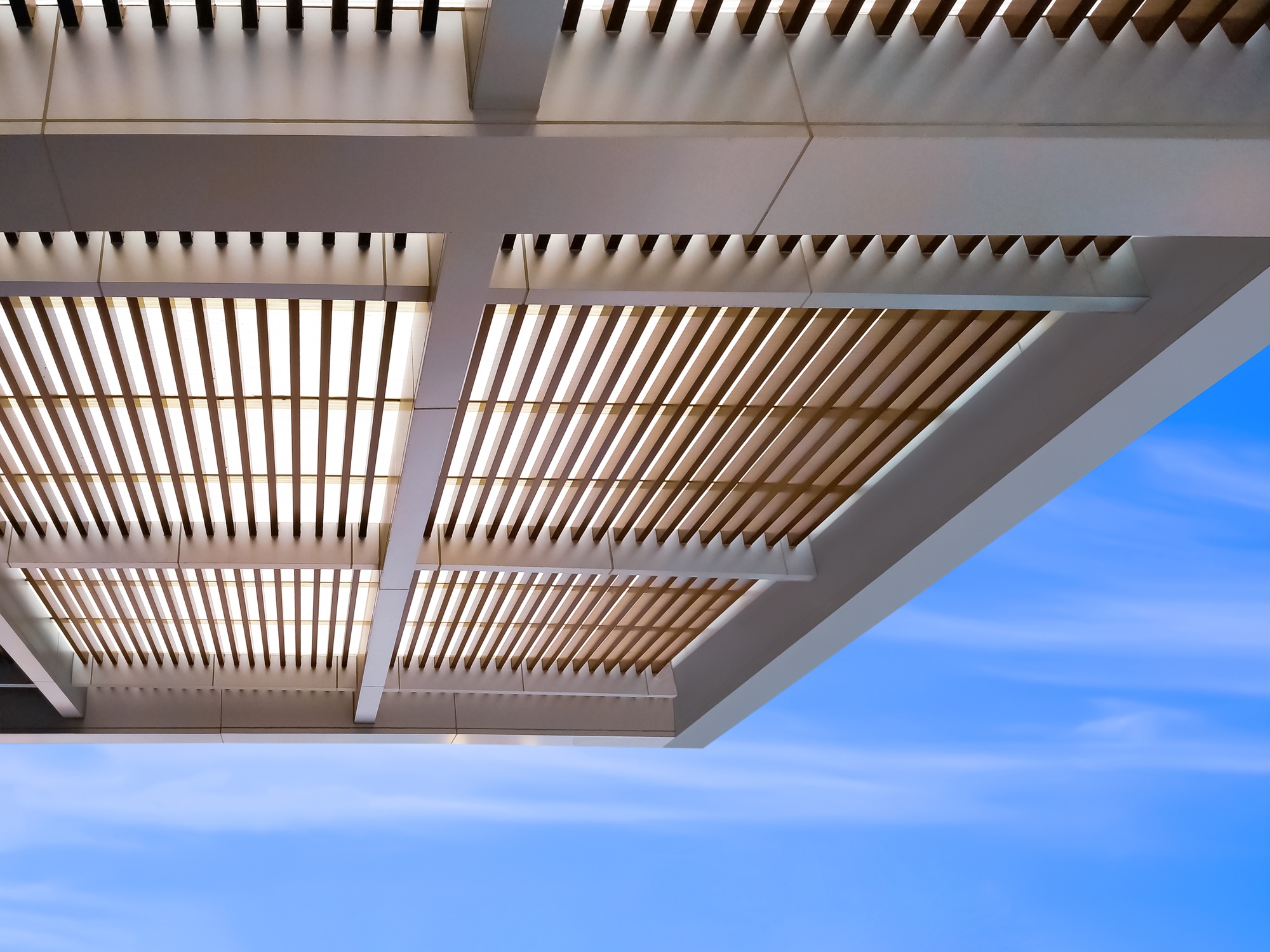 Modern battens roof awning outside of building against blue sky background